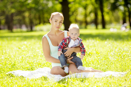 可爱的小宝宝在夏季公园与母亲在草地上。林瑞