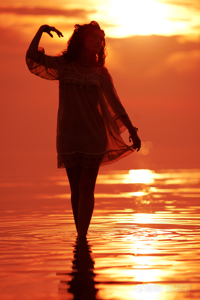 快乐自由的女人享受在海上日落背着
