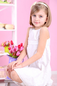 小女孩坐在小梯子上粉红的底色上的花朵