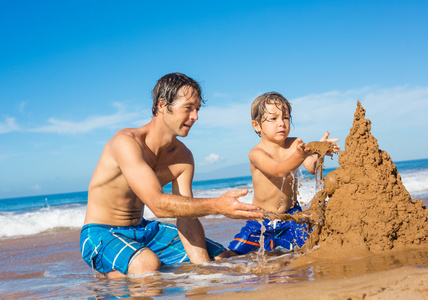 父亲和儿子在一起玩热带海滩上沙子