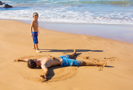 父亲和儿子在一起玩热带海滩上沙子