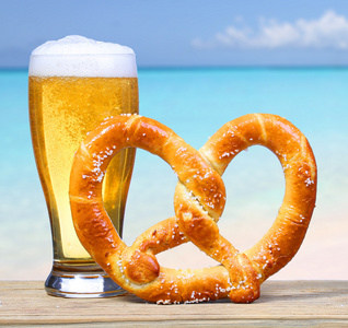 与德国椒盐卷饼在海景的啤酒杯。度假