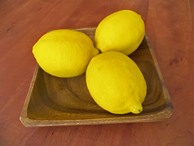 三个新鲜的柠檬，在一个木制的盘子上