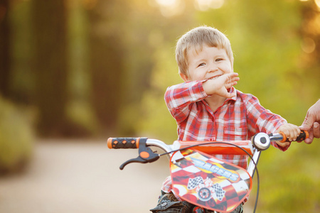 快乐的孩子骑着自行车在夏天公园