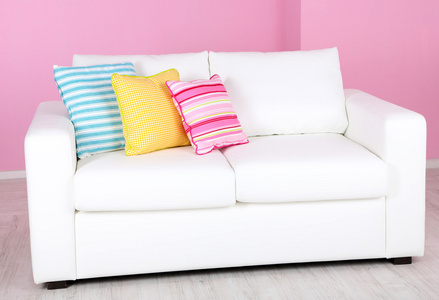 在房间里粉红色的背景上的白色沙发