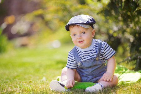 可爱的小男孩坐在草地上的肖像