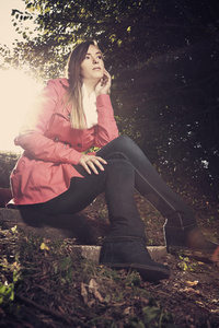 在粉红色的外套，坐在森林尽头的女孩