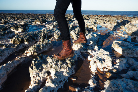紧靠在海边岩石间穿行的靴子