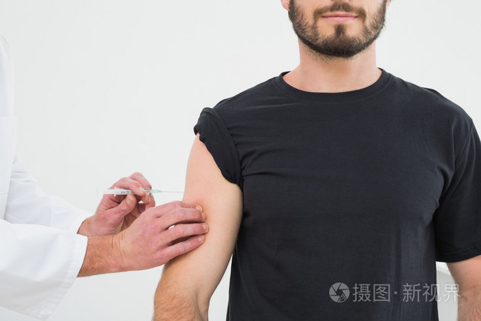 注射年轻的男性病人胳膊的手的特写镜头