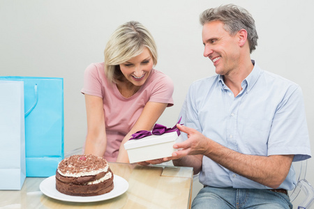 在蛋糕旁边一份生日礼物给一个幸福的女人的男人