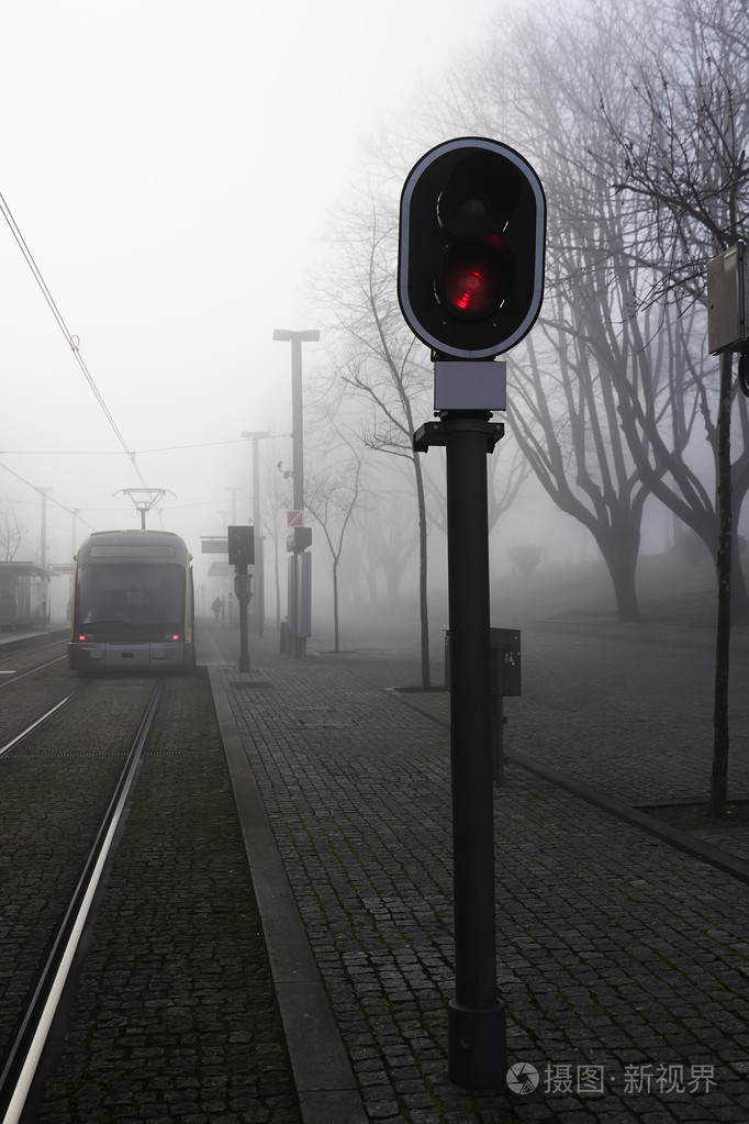 城市铁路跟踪与红色信号光雾黄昏