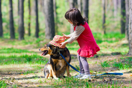 把帽子放在树林里的小狗的小女孩