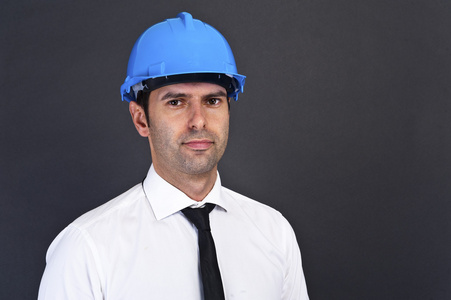 青年建筑工人在安全帽上的灰色背景