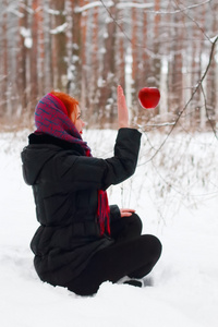 举手的女孩坐在雪地上，看着挂在天空