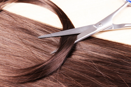 长长的棕色的头发和木制的背景上的剪刀