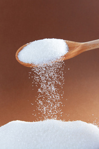 灰色的蛋糕杏仁在桌子的暗面上, 旁边是一勺糖和红糖碗