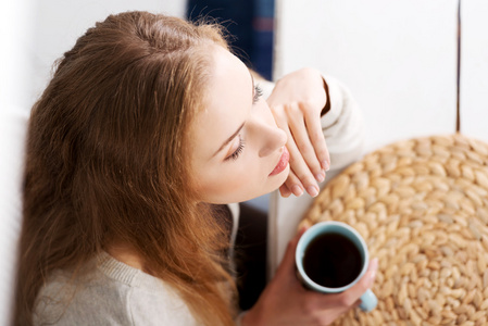 美丽的白种女人坐着杯咖啡桌旁