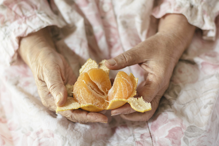 老妇人的手正在剥一个中国橙
