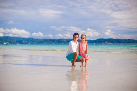 可爱的小女孩和年轻爸爸，在白色的沙滩上