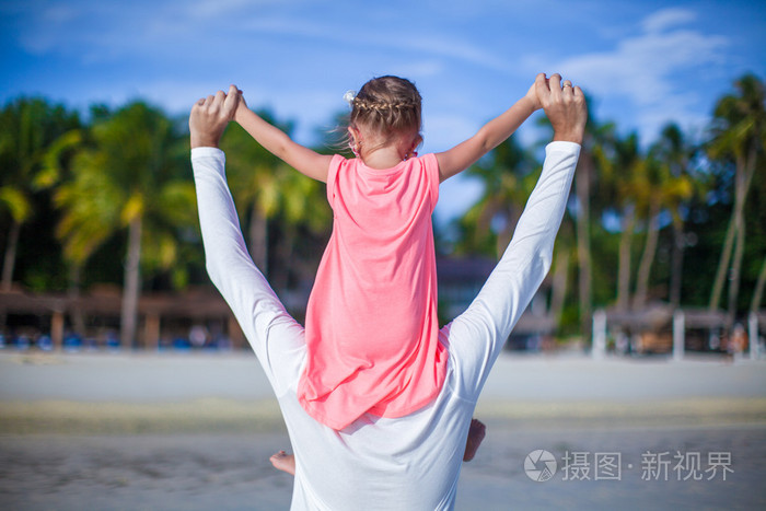 小女孩骑着她的父亲在海边散步