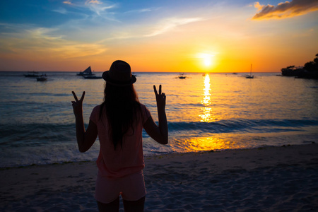 举的手，在日落时上岛长滩岛，菲律宾一名年轻女子的剪影