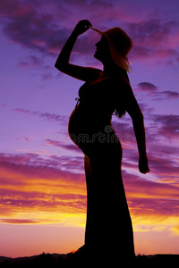 剪影女人怀孕触摸帽子一边一手向后