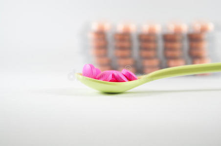 汤匙里的粉红色药片展示了医学概念