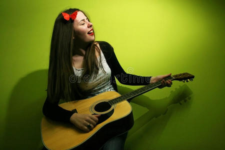 在绿色背景上弹吉他的黑发女人