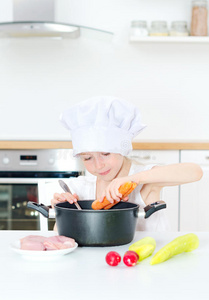 小女孩在厨师帽做饭。