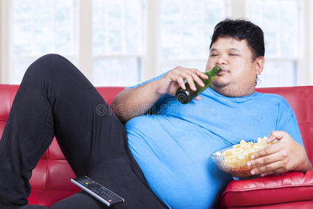 肥胖的男人懒洋洋地坐在沙发上