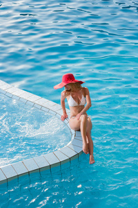 戴着红帽子的女人坐在游泳池里