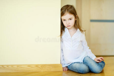悲伤的小女孩坐在地板上