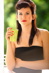 漂亮的女孩在室内喝茶或喝咖啡。绿色模糊背景