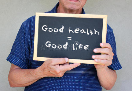一位老人举着黑板的特写镜头，上面写着健康等于好生活