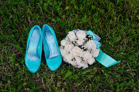 新娘花束和绿松石鞋放在绿草上