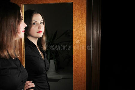 年轻的黑发女人在镜子前摆姿势
