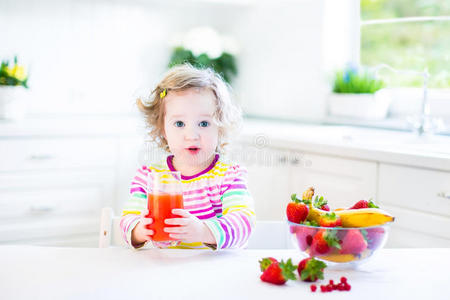 可爱的小女孩吃早餐喝果汁