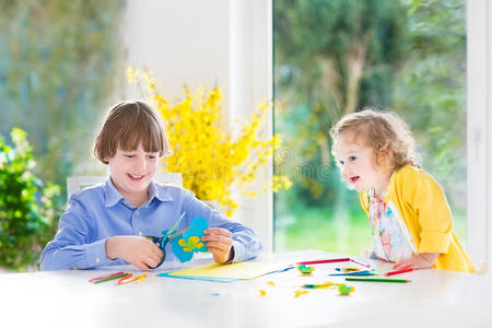 两个孩子画和剪彩色纸蝴蝶