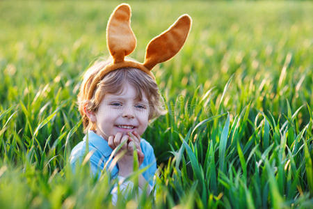 可爱的小孩在绿草中长着复活节兔子的耳朵