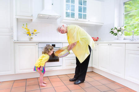 奶奶和迷人的女孩在白色的厨房里烤馅饼