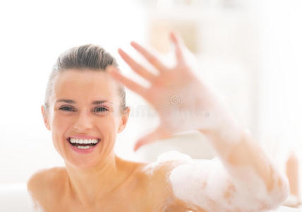 快乐的年轻女人在浴缸里露出泡沫