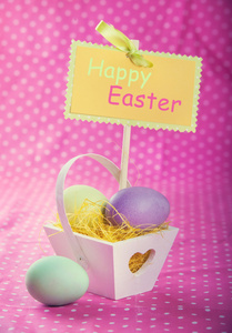 在紫色桌布的背景装饰篮子里的多彩复活节彩蛋。