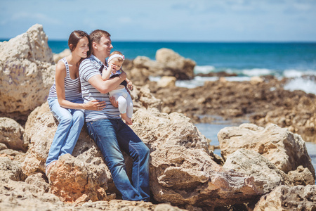 家庭的三个海洋岸边一起开心和享受着那景色的画像。户外活动