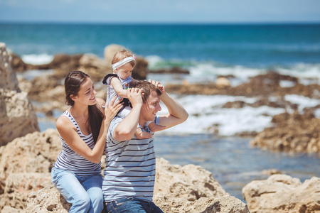 家庭的三个海洋岸边一起开心和享受着那景色的画像。户外活动