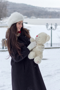 在下雪的天气中的开朗白种人年轻女人抱着一个玩具