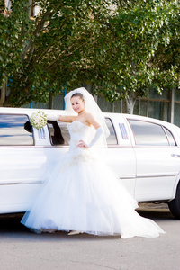 长长的白色婚礼在汽车附近的新娘