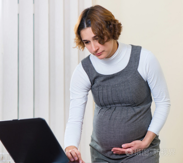在办公室工作的年轻孕妇