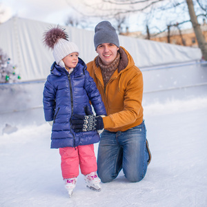 年轻快乐的父亲和可爱的小女孩，在一个溜冰场