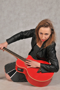 情感女孩用红色的吉他，在灰色的背景上