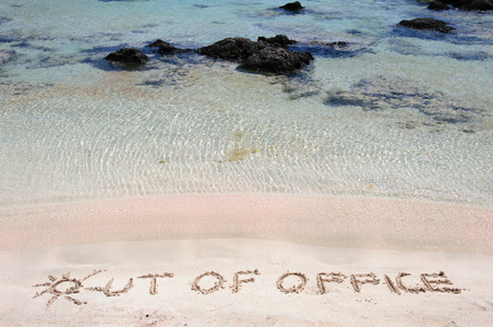 离开办公室写在美丽的海滩上的沙子上，蓝色的背景中的波